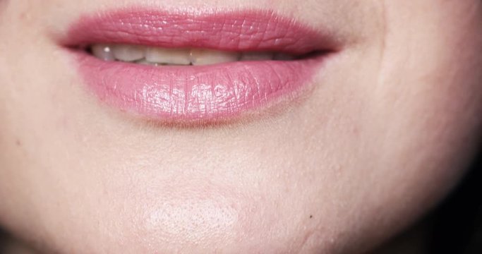 Close-up of unrecognizable woman with plump lips with lipstick making a kiss at camera and smiling.