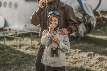 Happy little boy standing with binoculars near father