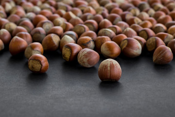 Selective focus of ripe hazelnuts on black with copy space.