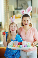 smiling elegant mother and daughter showing easter plate