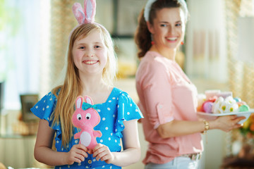 girl with rabbit toy and mother with easter plate in background