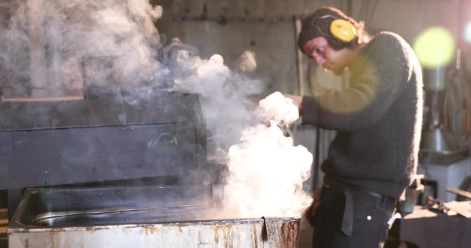 Bladesmith putting hot blades into water