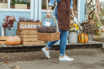 Woman florist in work clothes carrying plants