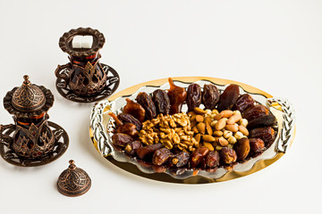 Luxury Dry Date Fruits,walnut,pistachio,hazelnuts and almonds in the stylish,golden tray with tea.Conceptual image of Islamic Tradition Ramadan.