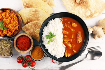 Chicken tikka masala spicy curry meat food in pot with rice and naan bread. indian food on table
