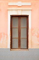 Simple tall wooden window in a pale pink wall.