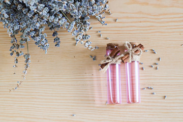 A bouquet of dried lavender flowers on the light purple surface with mini bottles