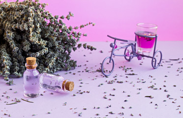 Essential Oil of Lavender in mini bottles on the pastel tone surface with dry lavender flower and mini bicycle