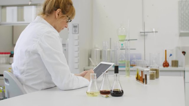 Close up of chemist working with hemp CBD oil and tablet in laboratory