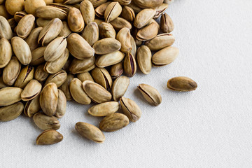 Fresh,crunchy shelled pistachios on the white fabric ground with copy space.