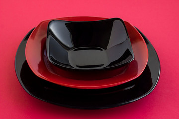 Designed meal service with red and black color,empty clean plates on red surface.