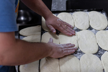 chef hands arranging raw bread dough on tray