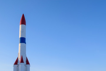 Rocket at the start. Four engines. Colors - red, white, blue. Glare of the sun, sky background. Concept of launching satellites into space, the threat of nuclear conflict.