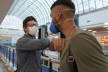 Travelers shake hands with their elbows to prevent disease transmission.