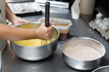 female cook hands whisking eggs for sweet cake preparation