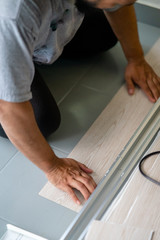 Kuala Lumpur, Malaysia - March 1, 2020: A man installing new vinyl tile floor, a DIY home project.