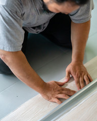 Kuala Lumpur, Malaysia - March 1, 2020: A man installing new vinyl tile floor, a DIY home project.