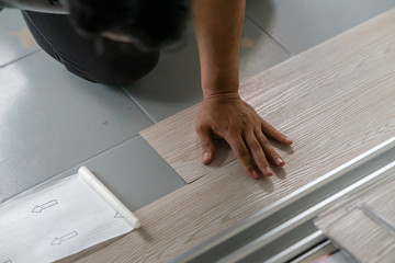 A person installing new vinyl tile floor, a DIY home project.