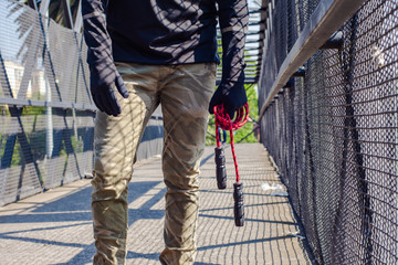 Person standing on a bridge holding a jump rope at urban place