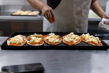 female cook hands preparing pizza