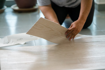 A person installing new vinyl tile floor, a DIY home project.