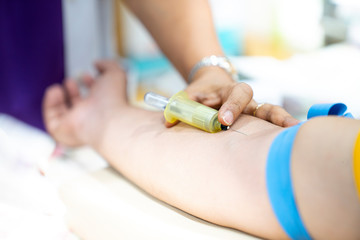 Medical person drawing blood with syringe and hypodermic needle from a patient.