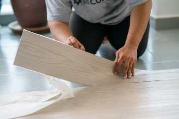 A person installing new vinyl tile floor, a DIY home project.