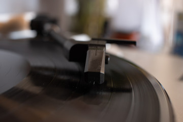 Fototapeta na wymiar Close up of turntable needle on a vinyl record. Turntable playing vinyl. Needle on rotating black vinyl.