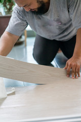 Kuala Lumpur, Malaysia - March 1, 2020: A man installing new vinyl tile floor, a DIY home project.