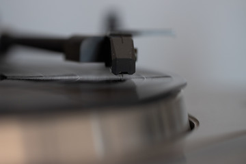 Close up of turntable needle on a vinyl record. Turntable playing vinyl. Needle on rotating black vinyl.