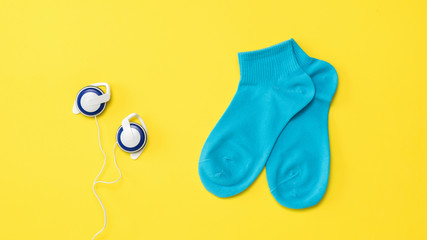 Blue sports socks and blue vintage headphones on a yellow background. Flat lay.