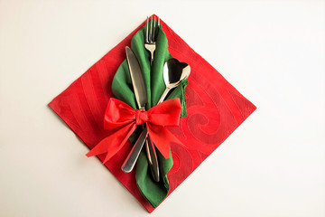 Green and red christmas napkin elegantly folded with cutlery set on white surface with copy space.Top view