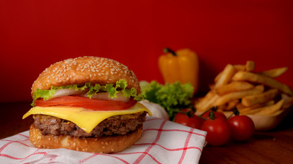 Close up view of beef burger with French fries and ingredients on rustic table