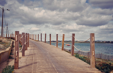 Fototapeta premium Algarve Faro coastline view. Wooden pathway, blue cloudy sky