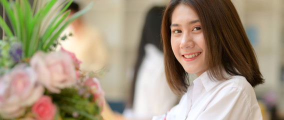 Side view of happy female university student sitting at wooden counter bar