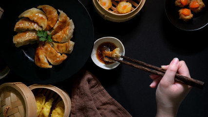 Top view of female eating Gyoza, dumplings and salted egg pork balls served with soy sauce