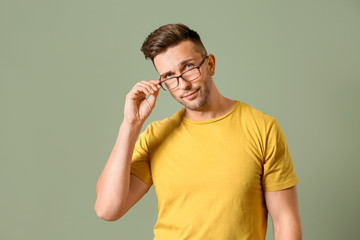 Young man wearing eyeglasses against color background