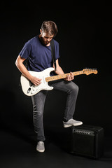 Obraz premium Young man playing guitar on dark background