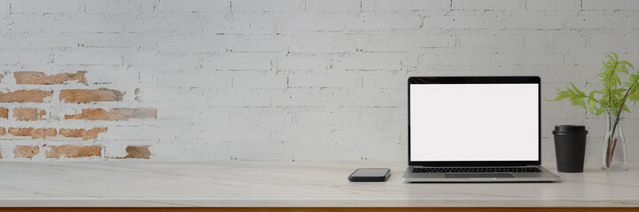 Cropped shot of contemporary workspace with blank screen laptop, smartphone, decoration and copy...