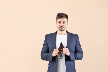 Sad man with empty purse on color background