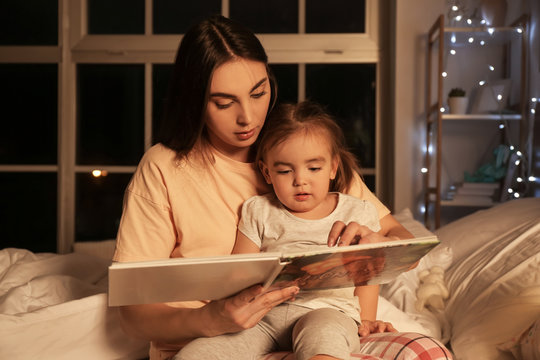 Mother And Her Little Daughter Reading Bedtime Story At Home