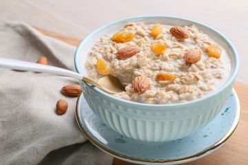 Bowl with tasty sweet oatmeal on table