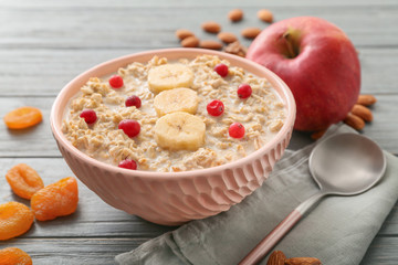 Bowl with tasty sweet oatmeal on table