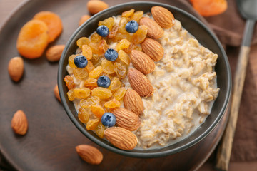 Bowl with tasty sweet oatmeal on table, closeup