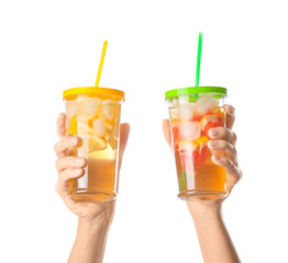 Female hands with cold tea in glasses on white background