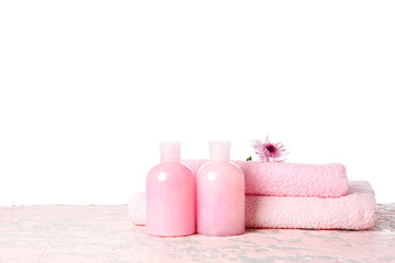 Fototapeta na wymiar Shampoo and towels on table against white background