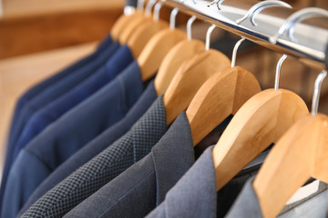 Obraz premium Hanger with different stylish male suits, closeup