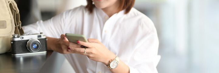 Close up view of young female photographer using smartphone