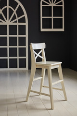 White chair on dark background.The wall is decorated with details in the form of arched doors and arched Windows.