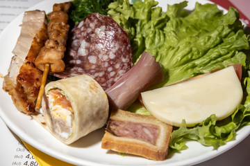 Meat and cheese snacks on a plate.